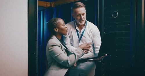 Colleagues Working in Server Room with Laptop