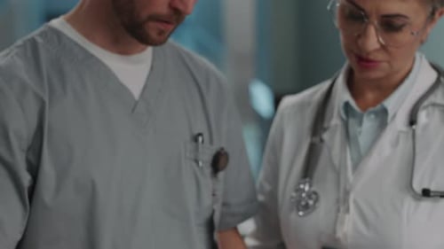 Two Doctors Using Tablet and Having Discussion in Hospital