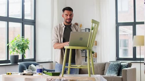Man Uses Laptop Near Repainted Chair Indoors