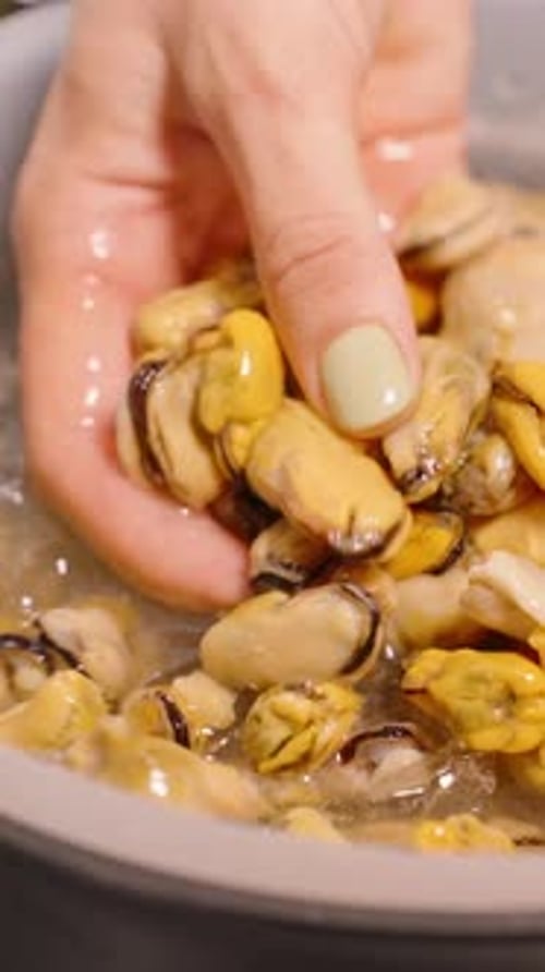 Vertical video. Slow Motion Hand Taking Mussels from Bowl of Water and Ice in Kitchen Close Up