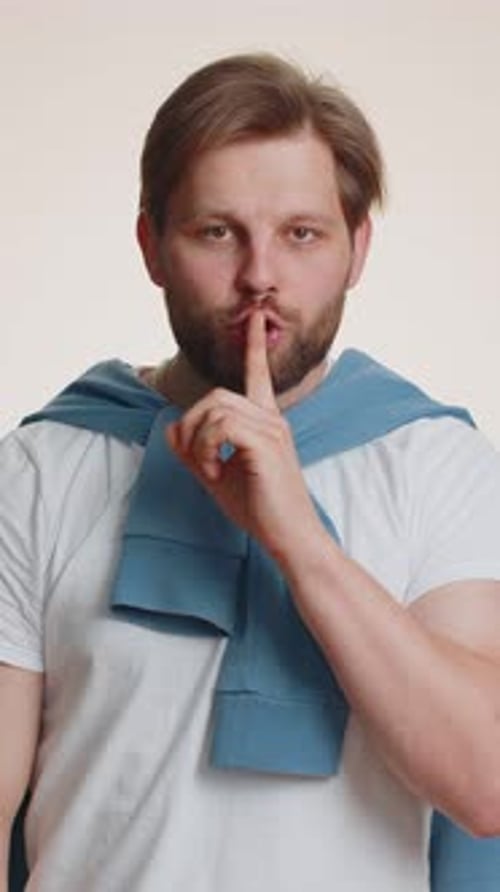 Young Bearded Man Presses Finger to Lips Makes Silence Gesture Sign Do Not Tells Secret Stop Gossip