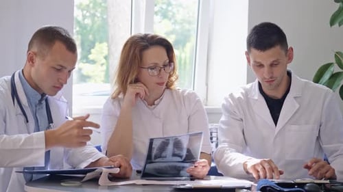 Team of Four Doctors Discusses the Results Chest XRay Scan of Patient in Consulting Room of Hospital