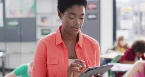Portrait of diverse female teacher and schoolchildren at desks in school classroom