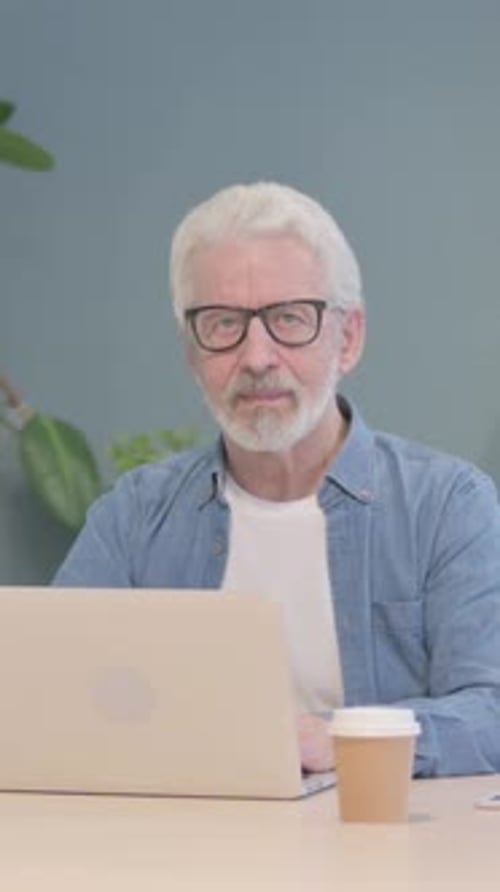 Smiling Mature Man Working on Laptop at Table