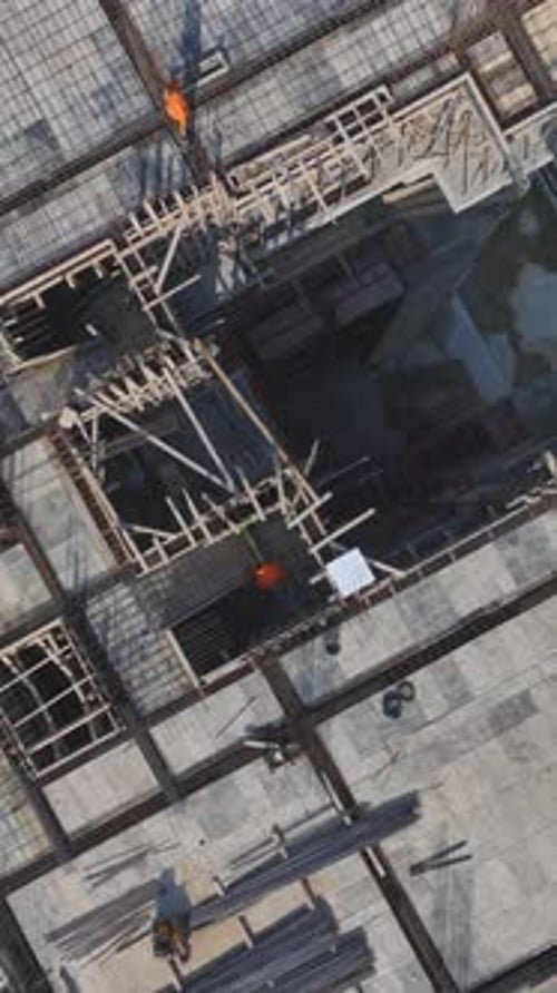 Equipos de vídeo verticales que colaboran en la construcción de paredes estructurales, hormigón y metalistería en un ajetreado