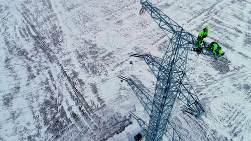 Workers Maintain Electricity Pylon in Snowy Field