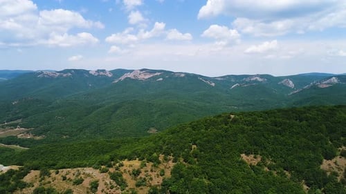 Panoramic View of Lush Green Mountains Under a Cloudy Blue Sky