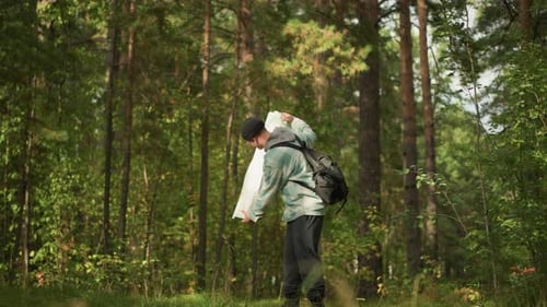 Male Hiker Plans Trail Using Compass and Map Hiker in Sunlit Clearing Meticulously Assesses Map and