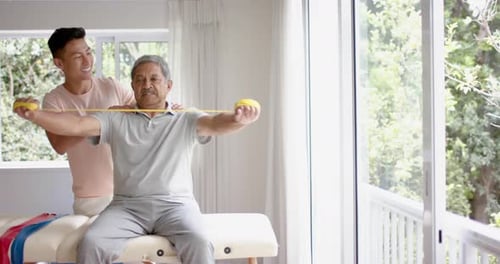 Senior Man Assisted by Young Adult with Resistance Band