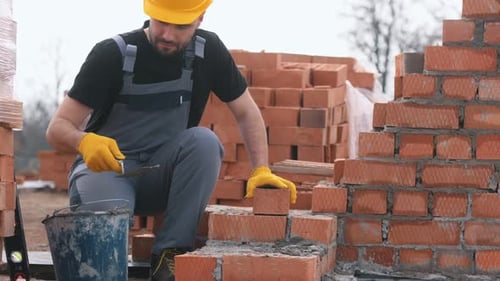 Bricklayer laying bricks on new construction site