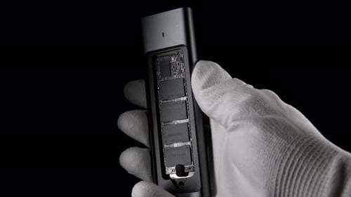 Hand Grasping Open SSD Case with Inside M2 External USB Drive on Black