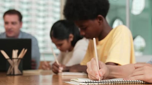 Children Writing in Notebooks in Classroom with Teacher