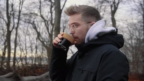 Man Drinks From Glass Outside in Nature