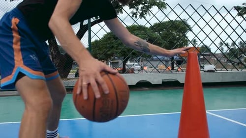 close-up male basketball player training with ball and sports cone