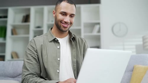 Man Smiling While Using Laptop at Home