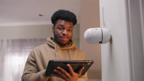 Mann richtet Sicherheitskamera mit Tablet ein