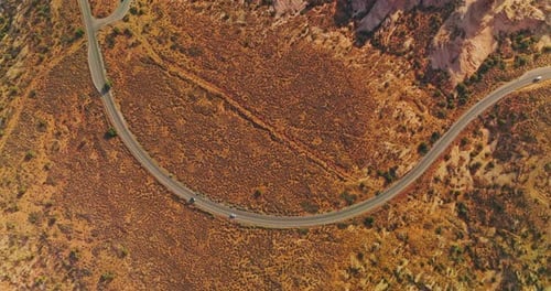 Curvy road through a desert near the weird rocks. Drone footage over the cars riding by the motorway