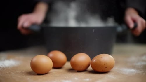 Flour Cascading Over Three Brown Eggs on Rustic Wooden Surface Professional Chef's Hands