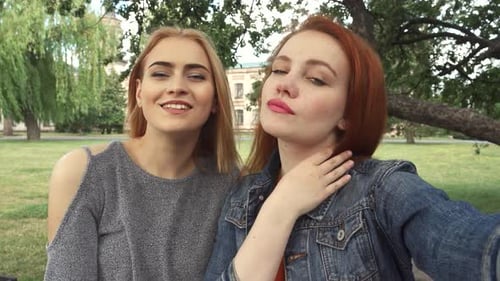 Zwei Mädchen nehmen freudig ein Selfie in einem sonnenbeschienenen Park auf