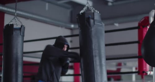 Man Boxer Training with Punching Bag in a Dark Boxing Gym Slow Motion Footage