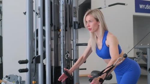 A Woman is Engaged in Exercising Using a Cable Machine at the Gym Showcasing Her Focus