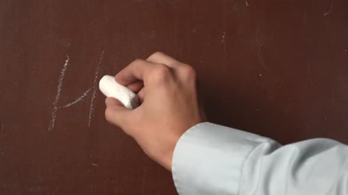 Hand Writes 'Hello' on Chalkboard with Chalk