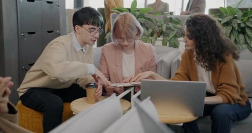 Young Adults Collaborating on Laptop in Modern Office