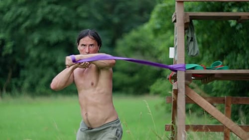 Shirtless Man Exercising Outdoors with Resistance Band