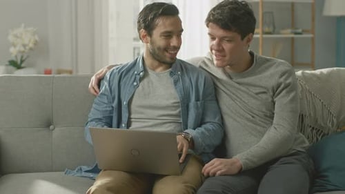 Two Young Men Using Laptop on Couch