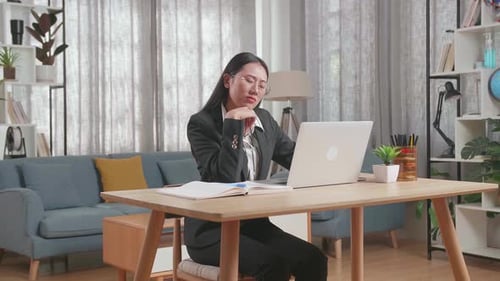 Woman Working From Home On Laptop Thinking