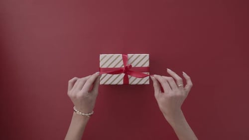 Hands Untying Red Ribbon on a Gift