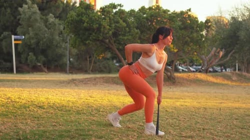 Woman Exercising with Resistance Band Outdoors During Sunset in Park