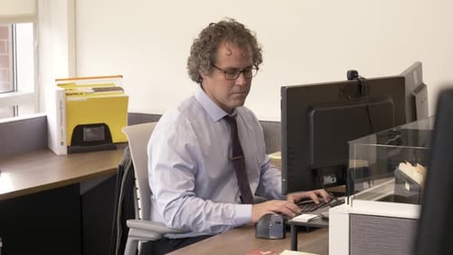 Mature businessman typing at his computer workstation in modern office