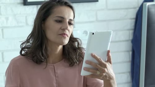 Woman Uses Tablet and Drinks Coffee Indoors