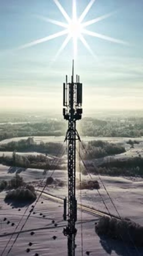 Tour de télécommunications au-dessus de la campagne enneigée sous un soleil radieux