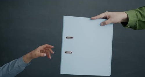 Closeup Slow Motion of Male Hand Giving Paper Folder to Female Against Black Color Background