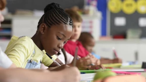 Cute Pupil Writing at Desk in Classroom at the Elementary School. Student