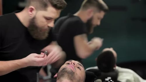 Barber Shaves Man in Barber Shop