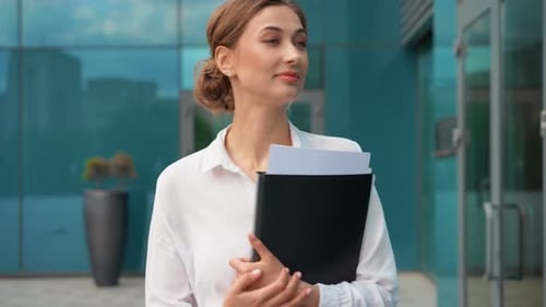 Confident Businesswoman Holding Folder While Walking Outside Office
