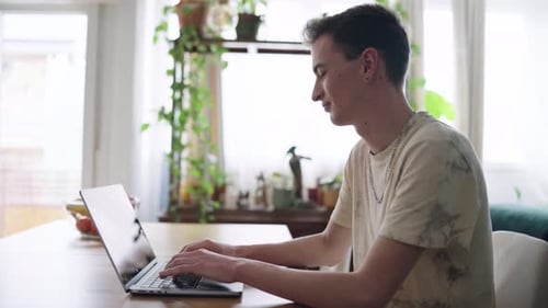Young Man Typing on Laptop in Bright Home