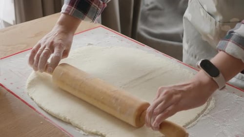 Woman Rolling Dough with Rolling Pin on Table
