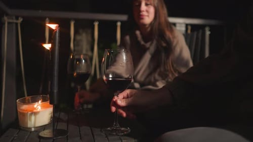 Un homme et une femme font tinter des verres à vin sur le toit de nuit