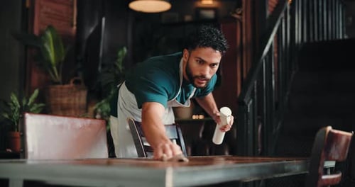 Man, waiter and cleaning table with cloth in cafe for hospitality, hygiene or sanitation