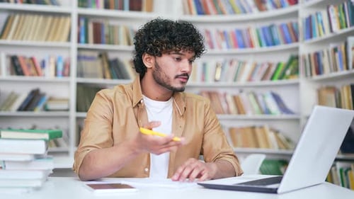 Young Adult Studying with Laptop in Library
