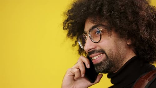 Portrait of Mature Man with Smartphone in a Studio on Yellow Background