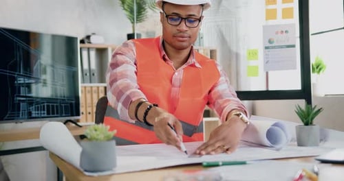 Man constructor in hardhat and vest drawing lines in building project working in modern office
