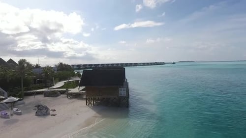 Foto de drone de vilas aquáticas na costa de um resort nas Maldivas. Água azul e turquesa. Full HD