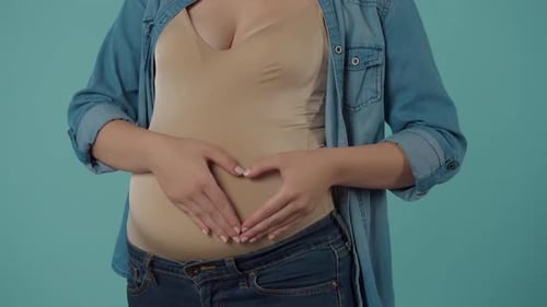 Une femme enceinte caresse son ventre gonflé avec amour et tendresse montre un signe cardiaque qui la met