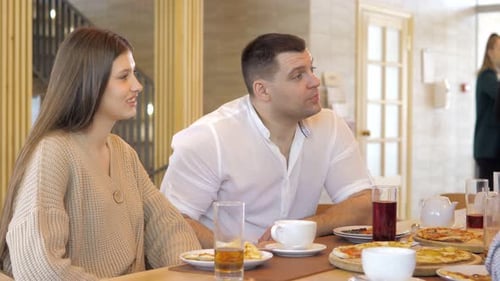 A Happy Group of Friends are Sitting at a Table in a Cozy Restaurant Laughing and Having Fun