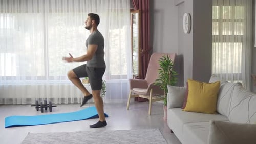 Professional runner doing cardio training at home by running on the spot wearing gym clothes.